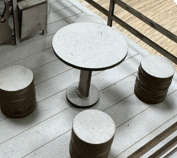 Scale model: a round table with stools on the deck.