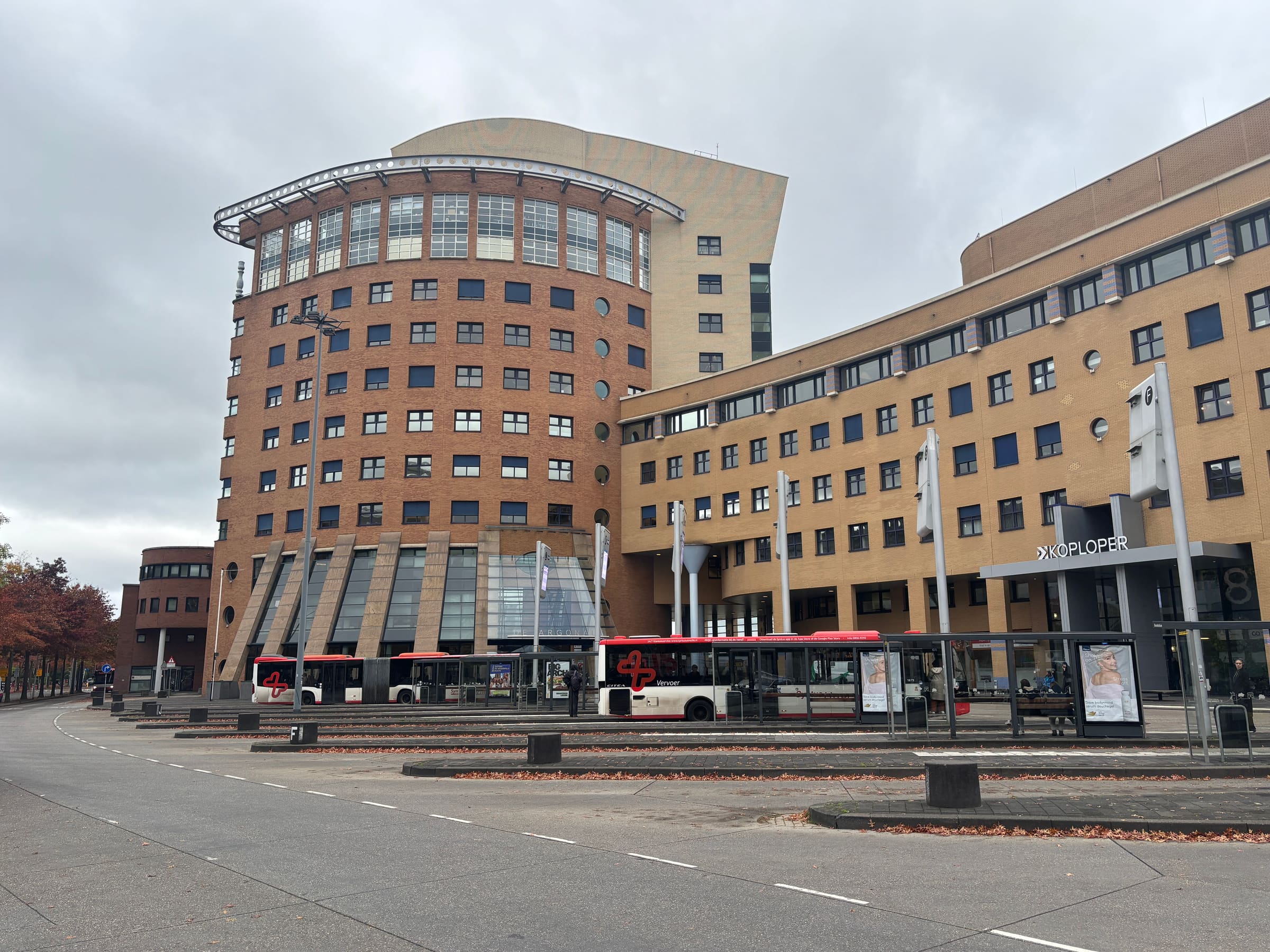 Bus stop Zonnewijzer in Nieuwland, Amersfoort: a wide street with bus shelters in front of the round brick apartment towers.