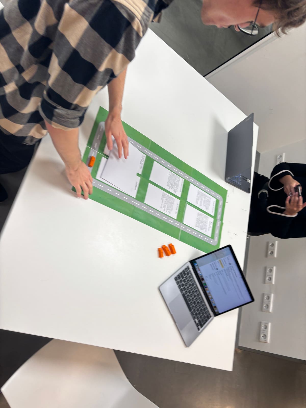 A tester moves the toy bus along the map while a teammate takes notes.