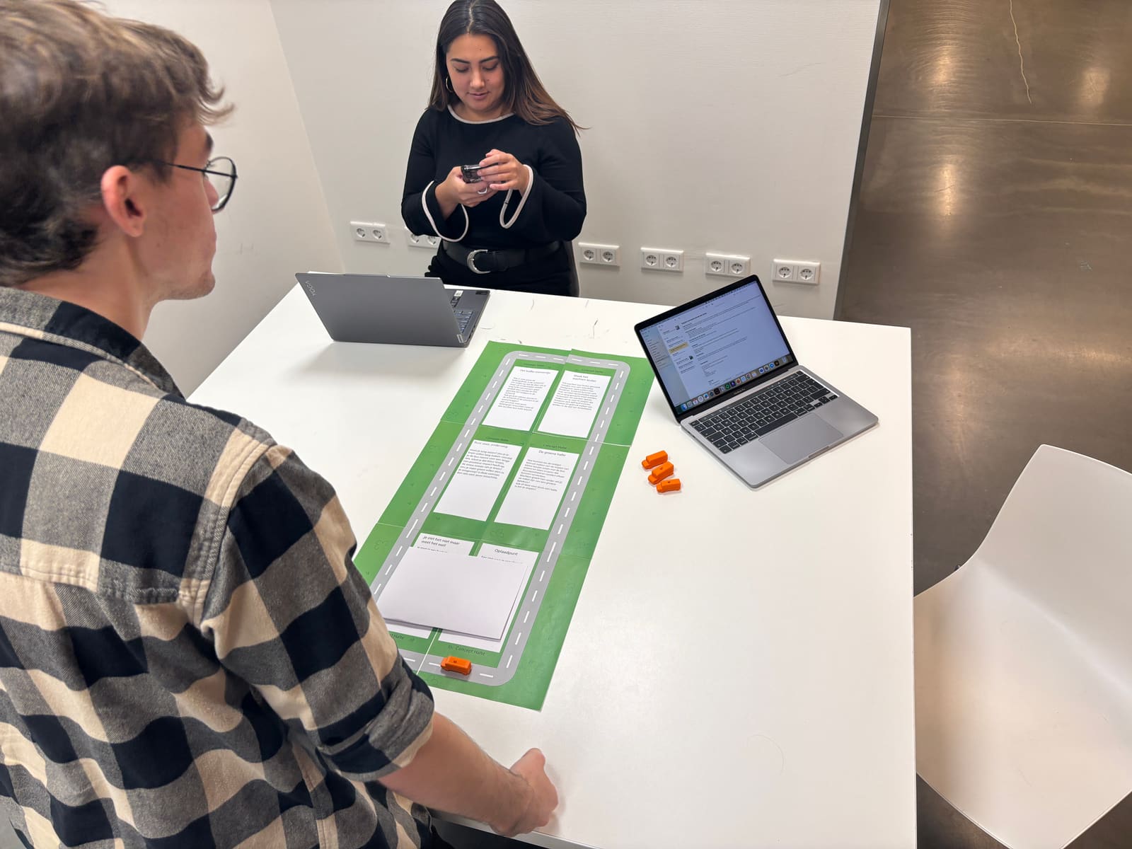 Two testers at a table with the green cardboard map of six concept stops.