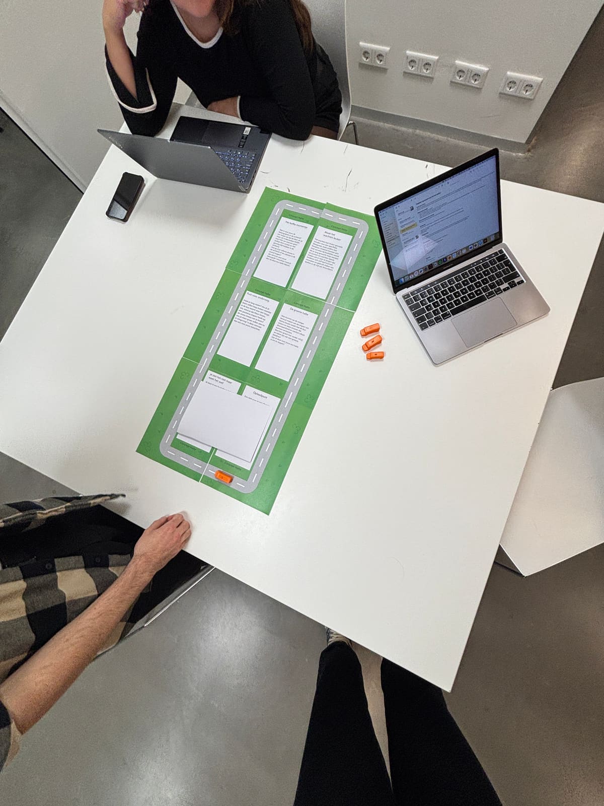 The board game from above: six concept cards along the route, laptops for notes.